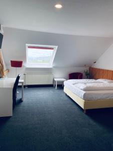 a bedroom with a bed and a desk and a window at Landhotel Zerlaut in Kißlegg