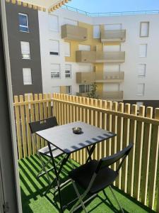 einen Tisch und Stühle auf einem Balkon mit einem Gebäude in der Unterkunft Bel appart T2 idéalement situé in Bondy