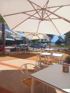 Terra Aurea Aparthotel في سالو: مجموعة طاولات وكراسي بمظلات بيضاء