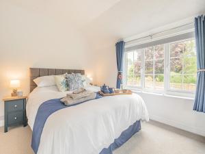 a bedroom with a bed with blue curtains and a window at The Firs in Carbis Bay