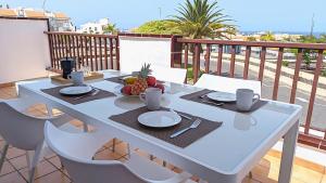 El Mirador Sea View - Air conditioning - Los Cristianos في لوس كريستيانوس: طاولة بيضاء مع وعاء من الفواكه على شرفة