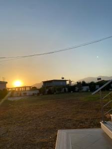 a sunset view of a field with a building and a house at Lori Gardenia Hotel in Stjar