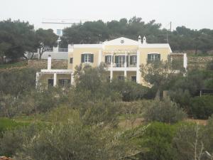 uma casa branca no topo de uma colina com árvores em Youth Ηostel Archipelagos - semi basement studio at Possidonia em Ano Syros