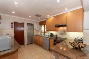 a large kitchen with wooden cabinets and stainless steel appliances at Kruger Park Lodge Unit No 308 with private pool - NYALA LODGE in Hazyview