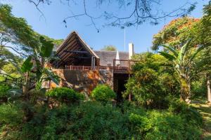 a house with a deck in the middle of trees at Kruger Park Lodge Unit No. 308 in Hazyview