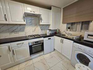 a kitchen with white cabinets and a washer and dryer at Lovely Flat close to Shepherd's Bush in London