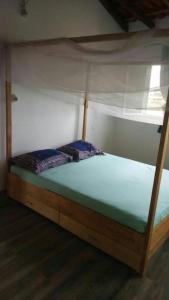 1 dormitorio con cama de madera y dosel en La case ronde avec Piscine -Ndayane en Ndéyane
