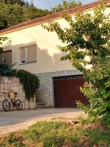 a bike parked in front of a house with a garage at Guest House Planinic in Čitluk
