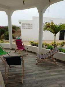 Ndéyane的住宿－La case ronde avec Piscine -Ndayane，海滩旁门廊上摆放着三把椅子