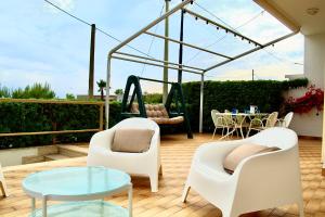 a patio with two chairs and a table and a swing at Villetta frontemare Torre Suda Salento in Torre Suda