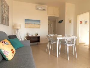 a living room with a couch and a table and chairs at Villetta frontemare Torre Suda Salento in Torre Suda