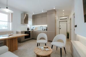 a kitchen with white chairs and a wooden table at Apartment Datala in Marina