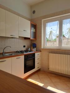 a kitchen with white cabinets and a sink and a window at La casa di mezzo-affitti brevi-zona ospedali in Busso
