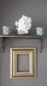 a gold picture frame with a vase of flowers on a shelf at Ma Campagne - Le Jardin in Auberville