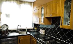 cocina con armarios de madera, fregadero y fogones en Ensuite With Kitchen Ext Large Room With Balcony in Zone 2 en Londres