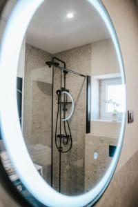 Apartment Datala في مارينا: دش في حمام مع مرآة مستديرة