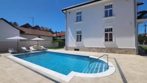 een zwembad voor een wit gebouw bij Vila Samokres sa bazenom in Banja Koviljača
