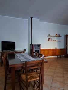 comedor con mesa, sillas y TV en La casa di mezzo-affitti brevi-zona ospedali en Busso