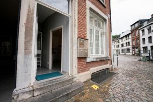 otwarte drzwi ceglanego budynku z niebieską matą na zewnątrz w obiekcie Studio L'Épicurien w mieście Spa