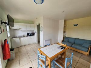 Gites 4,6 personnes Fécamp Etretat في Colleville: غرفة معيشة مع طاولة وأريكة زرقاء