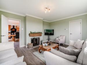 a living room with white furniture and a fireplace at Manor Farm Cottage in Hornby