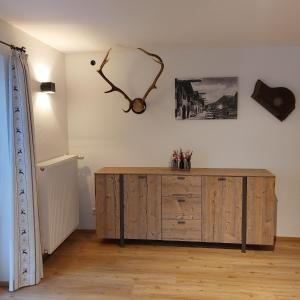 une pièce avec une armoire en bois et une horloge au mur dans l'établissement Haus Kurparkblick Ferienwohnung Lautersee, à Mittenwald