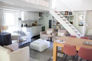 una sala de estar con muebles blancos y una escalera. en Cottage Markdal, en Breda