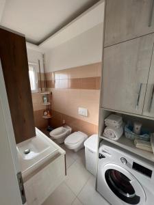 La salle de bains est pourvue d'un lave-linge et de toilettes. dans l'établissement Soleil Apartment with sunbed & umbrella, à Vlorë