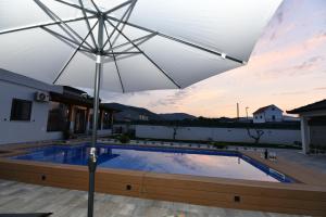 um grande guarda-chuva branco em cima de uma piscina em Palomino house em Sinj