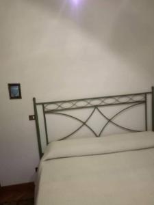 un letto bianco con testiera metallica in una stanza di Villa dolce a Massa