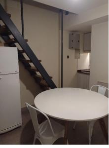 a white table and chairs in a room with a staircase at Departamento Lia in Guaymallen