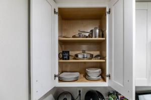 a kitchen with white cabinets with plates and pans at San Diego's Cozy Gem in San Diego