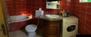 ein rot gefliestes Badezimmer mit einem Waschbecken und einer Waschmaschine in der Unterkunft Kuca za odmor DIVA in Mostar