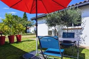 uma mesa com um guarda-chuva vermelho e uma cadeira azul em Studio indépendant, calme, avec parking privé et grand jardin, proche de Toulouse em Villeneuve-Tolosane