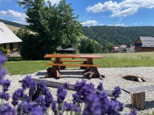 una mesa de picnic en un jardín con flores púrpuras en Chata Dolina v Bachledke en Ždiar