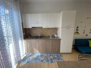 uma cozinha com armários brancos e um sofá azul em Caia Appartamenti Tropea em Tropea