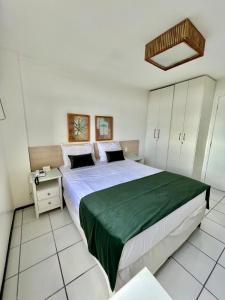 Un dormitorio con una cama grande con una manta verde. en Flat Gran Lençóis, en Barreirinhas