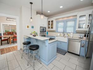 a kitchen with blue cabinets and two bar stools at The Cherry St House/Great amenities/near MSU in Springfield