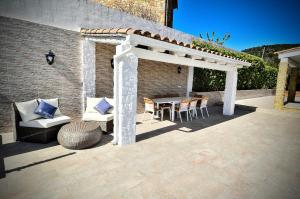 un patio con pérgola, mesa y sillas en Leng Vacation Home en Calonge