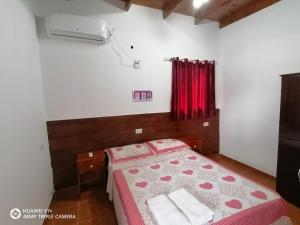 1 dormitorio con 1 cama con cortina roja en La Mulata Apart en Puerto Iguazú