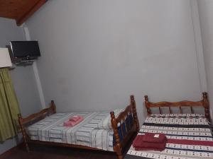 two twin beds in a room with a tv at Hospedaje Los Laureles in Wanda