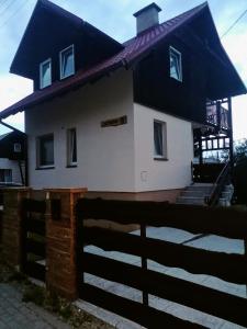 uma casa com um telhado preto e uma cerca em Apartament Charzykowy em Charzykowy