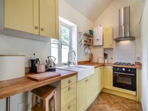 a kitchen with yellow cabinets and a sink at The Old Reading Room in Salhouse
