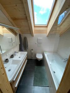 a bathroom with two sinks and a tub and a window at Chalet Montana Royal XL Koralpe in Hartelsberg