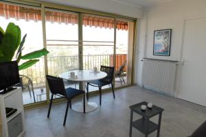 a living room with a table and chairs and a balcony at Charming T2 Eden Park with swimming pool private parking in Juan-les-Pins