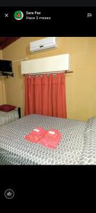 a bedroom with a bed with two red shirts on it at Hospedaje Los Laureles in Wanda