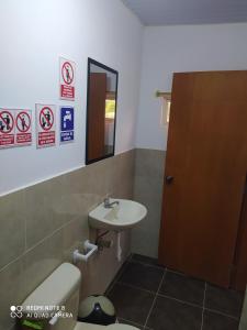 een badkamer met een wastafel, een toilet en een spiegel bij Estancia Spondylus in San Lorenzo