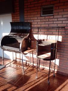 einen Grill und zwei Stühle neben einer Ziegelwand in der Unterkunft Hospedaje Los Laureles in Wanda