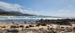 a beach filled with lots of rocks and the ocean at Mar de Queiruga: 01 As Seiras in Porto do Son