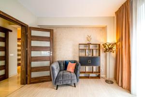 a living room with a chair and a book shelf at Pink Velvet RK Ghimbav in Ghimbav